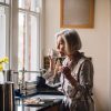 Retired woman drinking coffee alone in the morning in the kitchen wondering what to do with her time.