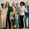 Group of 7 smiling professional older women approaching retirement age pose for a photo.
